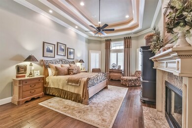 Primary bedroom with wood floors, fireplace, door to access pool and patio area,,plus plantation shutters throughout! 11 to 13 ft ceiling