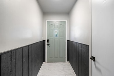 Entryway with wainscoting, wood walls, and light marble finish flooring