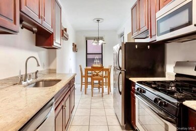 Kitchen with light stone counters, hanging light fixtures, light tile patterned floors, sink, and gas stove