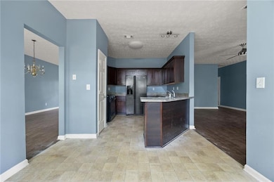 Kitchen featuring black appliances, dark brown cabinetry, a sink, a chandelier, and baseboards