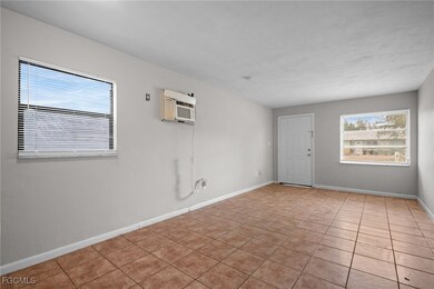 Tiled spare room featuring baseboards and a wall mounted AC