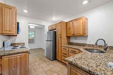 Kitchen with appliances with stainless steel finishes, light stone countertops, light tile patterned floors, recessed lighting, and a textured wall