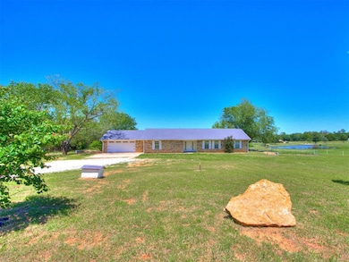 Ranch-style house featuring dirt driveway, a front yard, an attached garage, and a water view