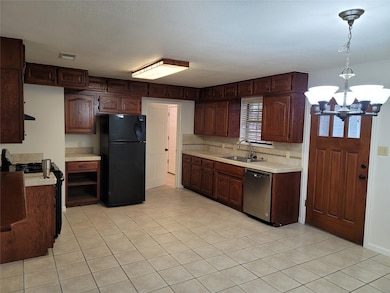 Kitchen with light countertops, freestanding refrigerator, gas range, pendant lighting, and dishwasher