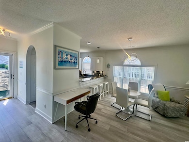 Dining space with a textured ceiling, light wood finished floors, arched walkways, and crown molding