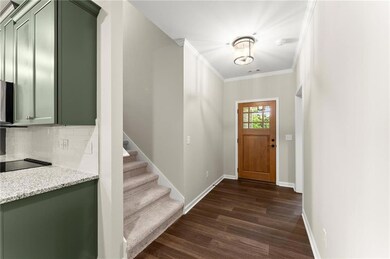 Foyer with dark wood-style flooring, crown molding, and stairway
