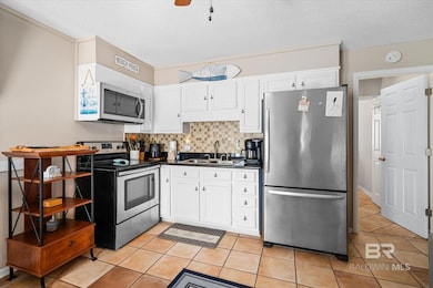 Kitchen featuring appliances with stainless steel finishes, tasteful backsplash, sink, and light tile patterned floors
