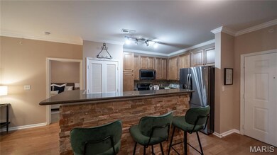 Kitchen with ornamental molding, appliances with stainless steel finishes, light wood-style floors, backsplash, and a breakfast bar