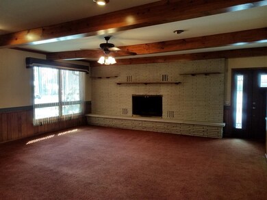 Enter into the existing family room with fireplace, wood beams, and separate entrance.