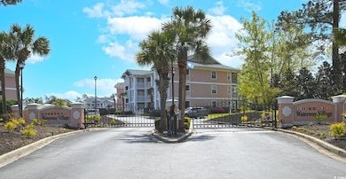 View of asphalt street featuring a gate, street li