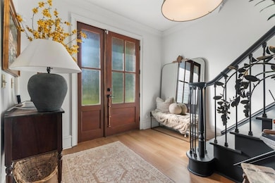 Foyer entrance featuring stairs, crown molding, plenty of natural light, and light wood-style floors
