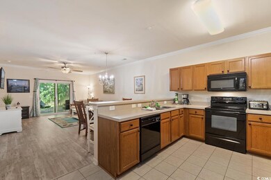 Kitchen with crown molding, black appliances, a peninsula, light countertops, and hanging light fixtures