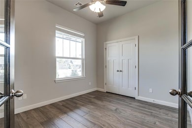 Unfurnished bedroom with wood finished floors, ceiling fan, a closet, and french doors