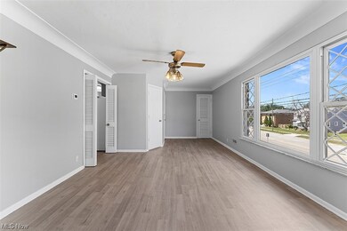Empty room with ceiling fan, light hardwood / wood-style flooring, and crown molding