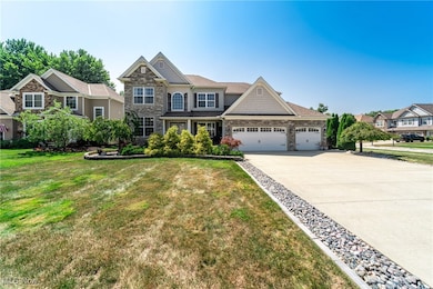 Craftsman-style house with stone siding, a garage, driveway, and a front yard