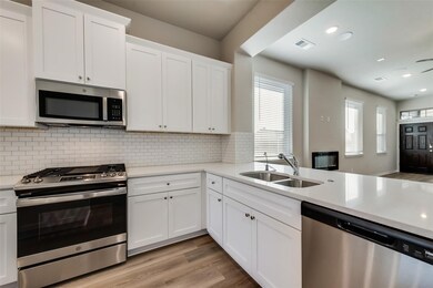 Kitchen with stainless steel appliances, light wood-style flooring, white cabinetry, light stone counters, and recessed lighting