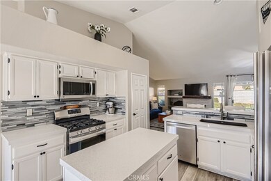 Quartz countertops, tiled backsplash, stainless steel appliances and white cabinetry.