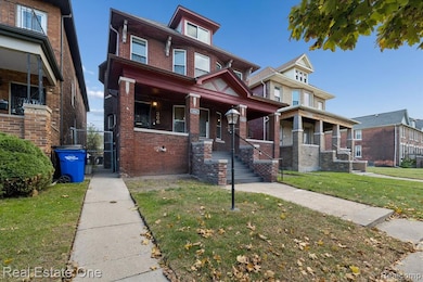 View of front of house featuring brick siding, a front yard, a gate, and covered porch