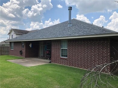 Rear view of house featuring a shingled roof, a patio area, and brick siding