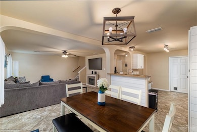 Dining space featuring arched walkways, ceiling fan, and a chandelier