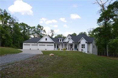 Modern farmhouse style home with a porch, driveway, a front lawn, board and batten siding, and roof with shingles