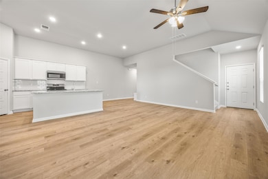 Unfurnished living room featuring light wood-style flooring, a ceiling fan, recessed lighting, vaulted ceiling, and stairs