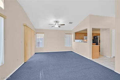 Unfurnished living room featuring light carpet, a ceiling fan, lofted ceiling, and light tile patterned floors