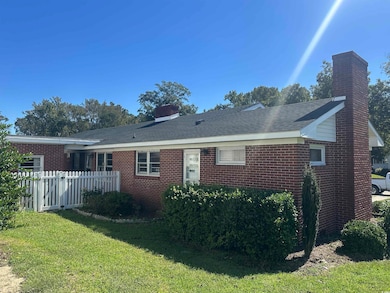 Rear view of property with a chimney, brick siding, and a shingled roof
