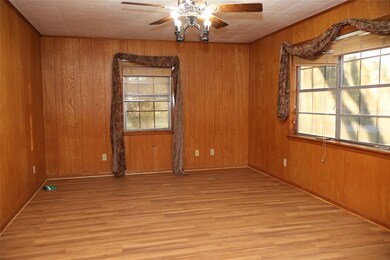 Unfurnished room with wood walls, light wood-type flooring, and a ceiling fan