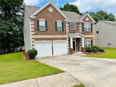 View of front of home featuring brick siding, concrete driveway, an attached garage, and a front yard