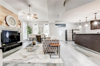 Downstairs living room featuring ceiling fan, light hardwood / wood-style floors, ornamental molding, and sink
