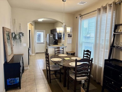 Dining space featuring light tile patterned floors and arched walkways