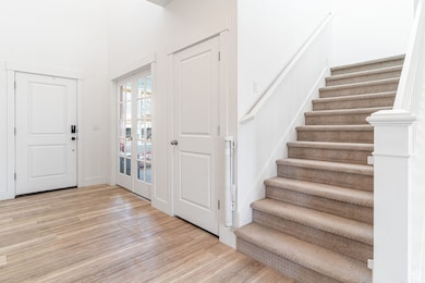Foyer featuring wood finished floors, stairs, and french doors