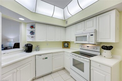 Kitchen with white appliances, light tile patterne