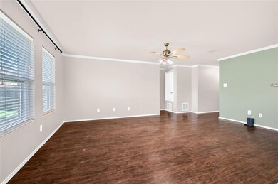 Empty room with ceiling fan, crown molding, dark wood-type flooring, and a wealth of natural light