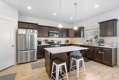 Kitchen featuring dark brown cabinets, stainless steel appliances, pendant lighting, a kitchen bar, and recessed lighting