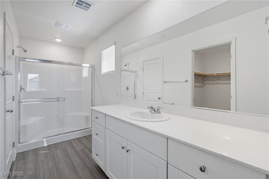 Full bath featuring a stall shower, vanity, dark wood finished floors, and a spacious closet
