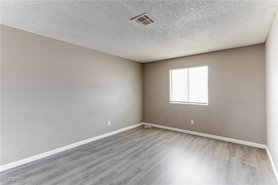 Unfurnished room with light wood-type flooring and a textured ceiling