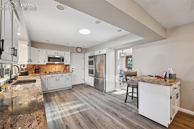 Kitchen with granite stone counters, a kitchen bar, granite backsplash, and luxury vinyl flooring