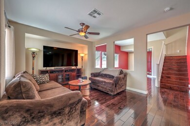 Family room with a ceiling fan, stairs, and dark h