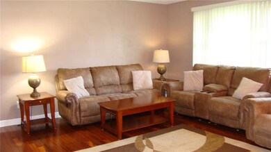 Spacious living room with large window and hardwood floor.