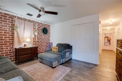 Living room featuring ceiling fan, brick wall, and
