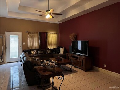 Tiled living room featuring a tray ceiling and ceiling fan