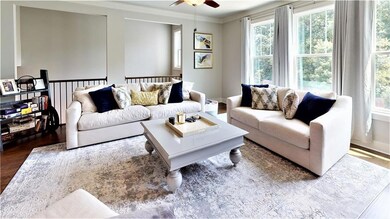Living area featuring wood finished floors, ceiling fan, and ornamental molding