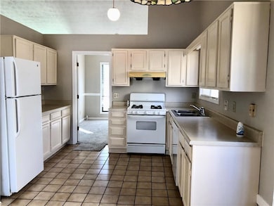 Kitchen with white appliances, a sink, under cabin