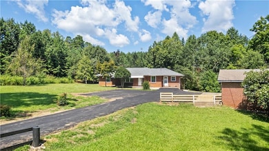 Single story home featuring brick siding, a wooded view, and asphalt driveway