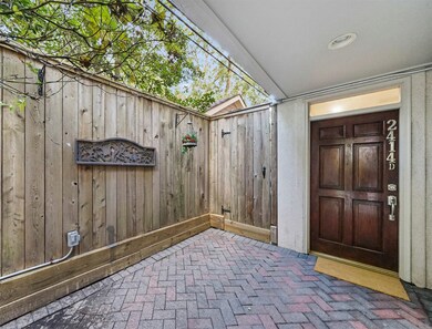A wrought iron gated entrance flanked by coach lan