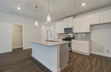 Kitchen with stainless steel appliances, decorative backsplash, light stone countertops, decorative light fixtures, and white cabinetry
