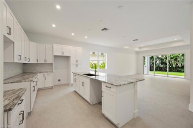 Kitchen featuring white cabinets, decorative backsplash, light stone counters, a tray ceiling, and recessed lighting