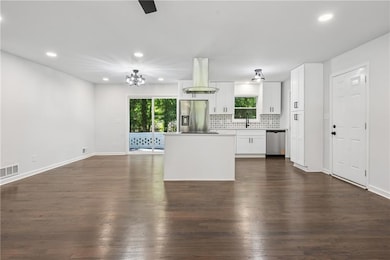 Kitchen with appliances with stainless steel finishes, island exhaust hood, recessed lighting, dark wood-style floors, and tasteful backsplash